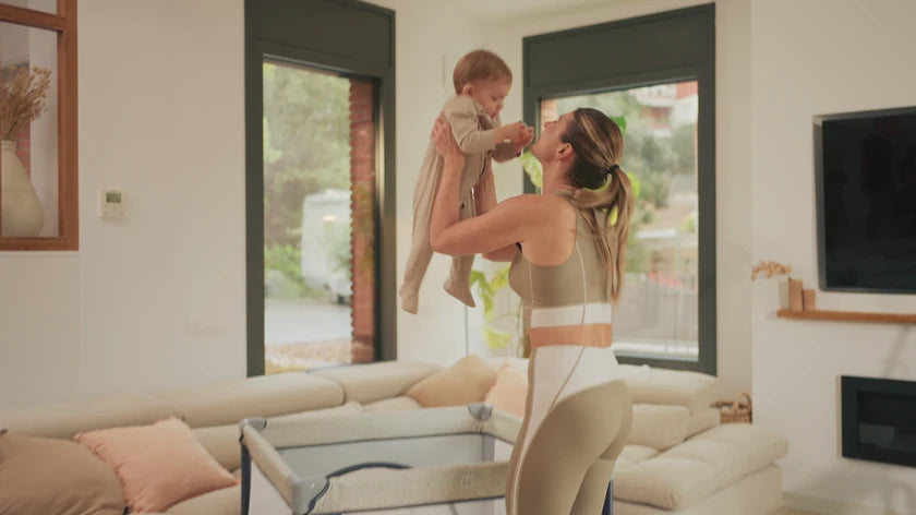 A mother lifting her baby in the lounge at home